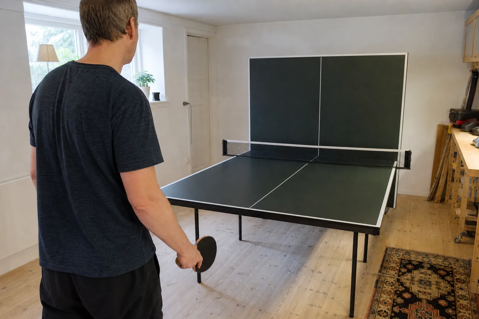 En vuxen sedd bakifrån vid ett pingisbord med ena bordshalvan uppfälld.