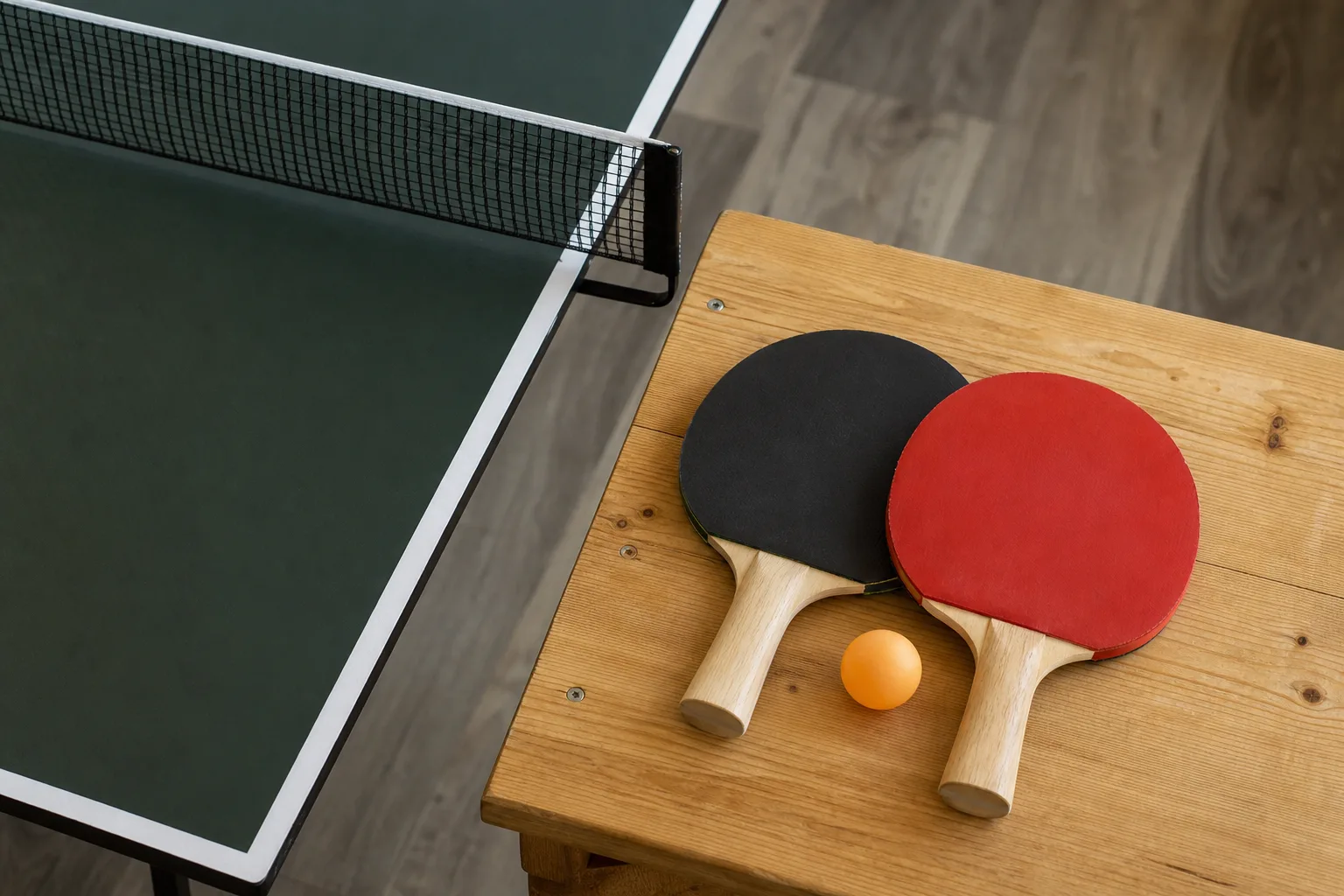 Pingisrack och en boll på en bänk intill ett pingisbord.